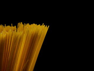 Grop of raw spaghetti on black background, copy space for text.