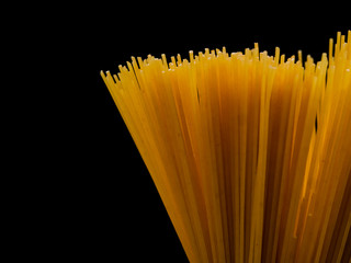 Grop of raw spaghetti on black background, copy space for text.