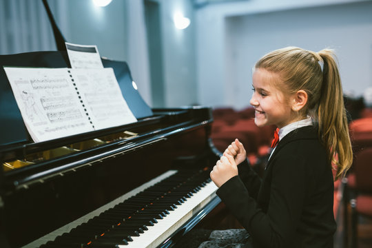 happy little girl teaching to play piano in music school - Powered by Adobe