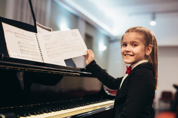 little girl teaching to play piano in music school