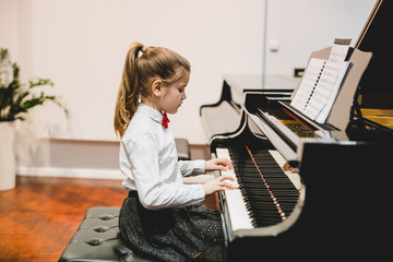 cute little girl elegant dressed playing concert piano