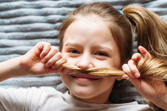 Portrait of pretty girl lying on gray carpet. Happy childhood.