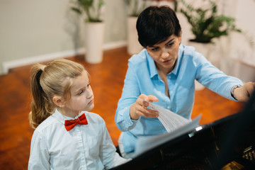 little girl teaching to play piano with her music teacher