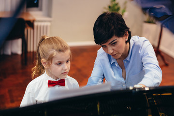 little girl teaching to play piano with her music instructor