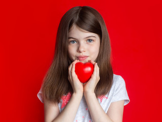 сute young girl holding a red heart, concept of medicine, childhood, donations, Valentine's Day - on red background