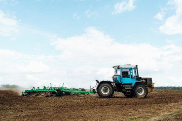 Fototapeta premium The tractor works in the field. The release of grass with a tractor. Farmer's work