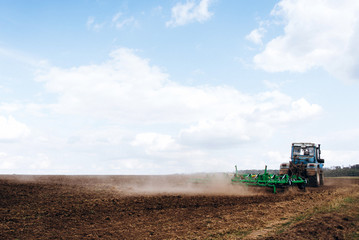 Fototapeta premium The tractor works in the field. The release of grass with a tractor. Farmer's work