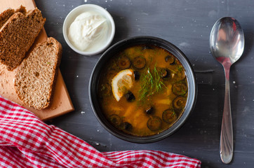 pickle soup with olives, tomatoes and lemon served with cream and bread. Proper nutrition diet healthy food