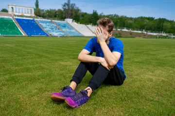 Fototapeta na wymiar tired male athlete sportsman relax on the grass field after practices