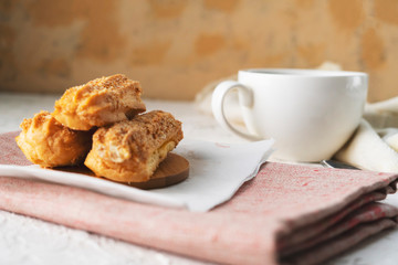 morning snack with coffee and creamy eclair on a table with white tablecloth, business breakfasts