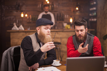 Two talented bearded men working on their free time in a coffee shop