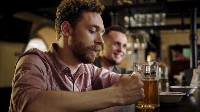 Cheerful friends drinking draft beer in a pub