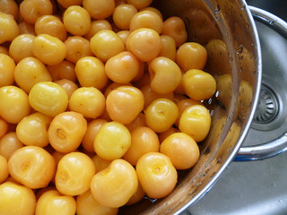 Ripe Sweet Cherries in metal colander with water drops. Close-up of fresh yellow and pink sweet cherries in colander on gray sink surface. Fresh summer background. 