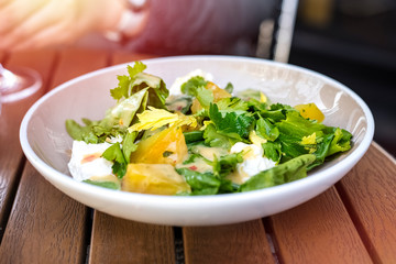 Fresh salad in a plate of vegetables and greens with mozzarella cheese pieces. Ready meal