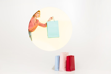 beautiful stylish young woman holding shopping bag on white with yellow circle and copy space