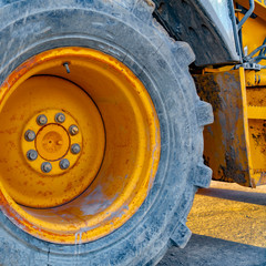 Square Close up of the wheel of a yellow loader parked on the road on a sunny day