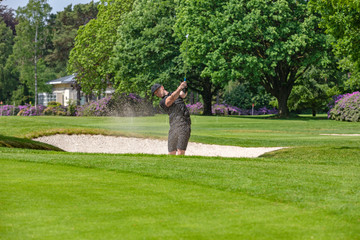 Golfer schlägt aus Bunker ab
