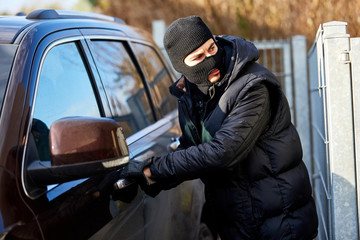 Autodieb prüft Tür am Auto