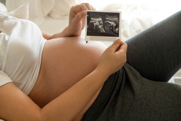 Pregnant woman feeling happy at home while taking care of her child. The young expecting mother...