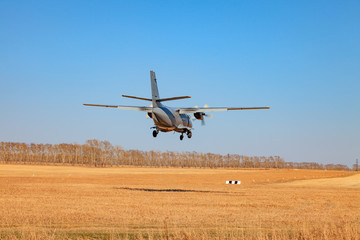 A small aircraft for the transport of passengers and paratroopers lands in a field on a landing...