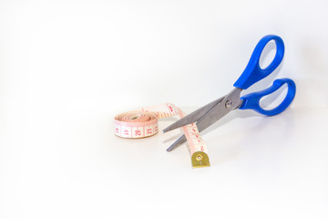 Scissors cutting measuring tape over white background. Work lifestyle concept. Body care.
