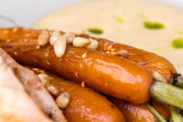Young carrots fried in hot oil and decorated with pine nuts. Close up