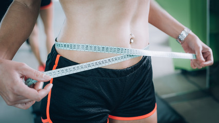 Fit fitness woman measuring her waistline with measure tape