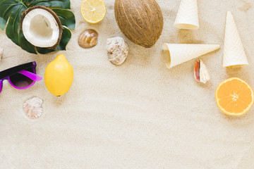 Fototapeta na wymiar Sunglasses with exotic fruits and shells on sand