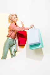 beautiful stylish girl smiling and posing with shopping bags on white with yellow circle