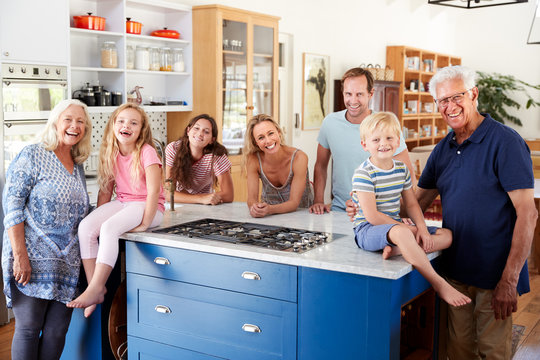 Portrait Of Multi Generation Family Standing Around Kitchen Island Together