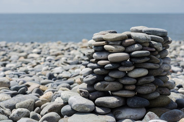big tower of stones on the coast of the sea with pebbles