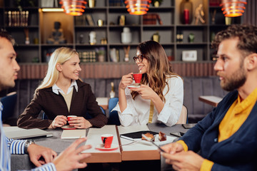 Group of multiethnic colleagues sitting at restaurant and talking about new project. Start up business concept.