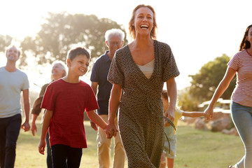 Multi-Generation Family Walking In Countryside Against Flaring Sun