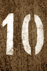 Number 10 in stencil on metal wall in brown tone.
