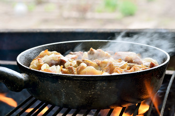 Cooking meat in a pan with onions on the grill. Fried pork