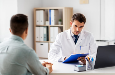 medicine, healthcare and people concept - doctor with clipboard and male patient at medical office in hospital