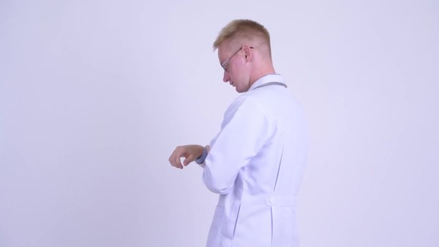 Happy Young Blonde Man Doctor Turning Around And Waving Hand