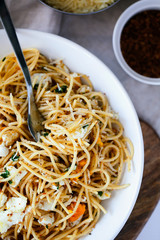 Quick and delicious italian pasta spaghetti with fried eggs, pangrattato and grated parmesan on white plate close-up top view.Fresh homemade food. Italian healthy food concept.Vertical orientation