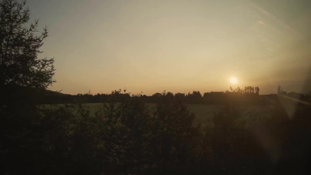 Farms, fields, landscapes and a small city seen from a sightseeing train - panoramic view during sunrise - slow motion.