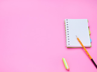 top view of the table of a teenage child, the composition of a notebook pencil eraser on a pink background