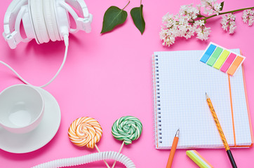 top view of the table of a teenage child, composition of pencil for laptop eraser flower glass with drink earphone Lollipop on pink background