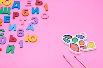 top view of the child's table, the composition of the paint brush letters numbers on a pink background