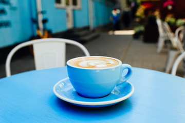 Blue cup of aromatic coffee on a blue table.