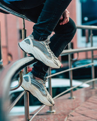 Man sitting on a fence wearing jeans and sneakers