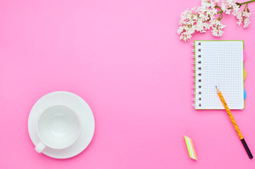 top view of the table of a teenage child, the composition of the pencil notebook eraser flower empty glass on a pink background