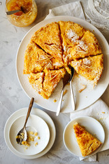 Traditional English lemon pudding cake with lemon twist and powdered sugar on a white plate on a light background top view.Homemade fruit pastries for the holiday dinner table.Vertical orientation