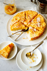 Traditional English lemon pudding cake with lemon twist and powdered sugar on a white plate on a light background top view.Homemade fruit pastries for the holiday dinner table.Vertical orientation