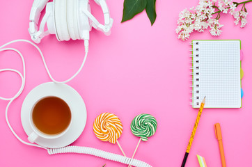 top view of the table of a teenage child, composition of pencil for laptop eraser flower glass with drink earphone Lollipop on pink background