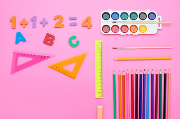 top view of the child's table, the composition of the paint brush letters numbers color pencils eraser different line on a pink background