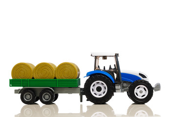 farm tractor toy with hay trailer, isolated on white